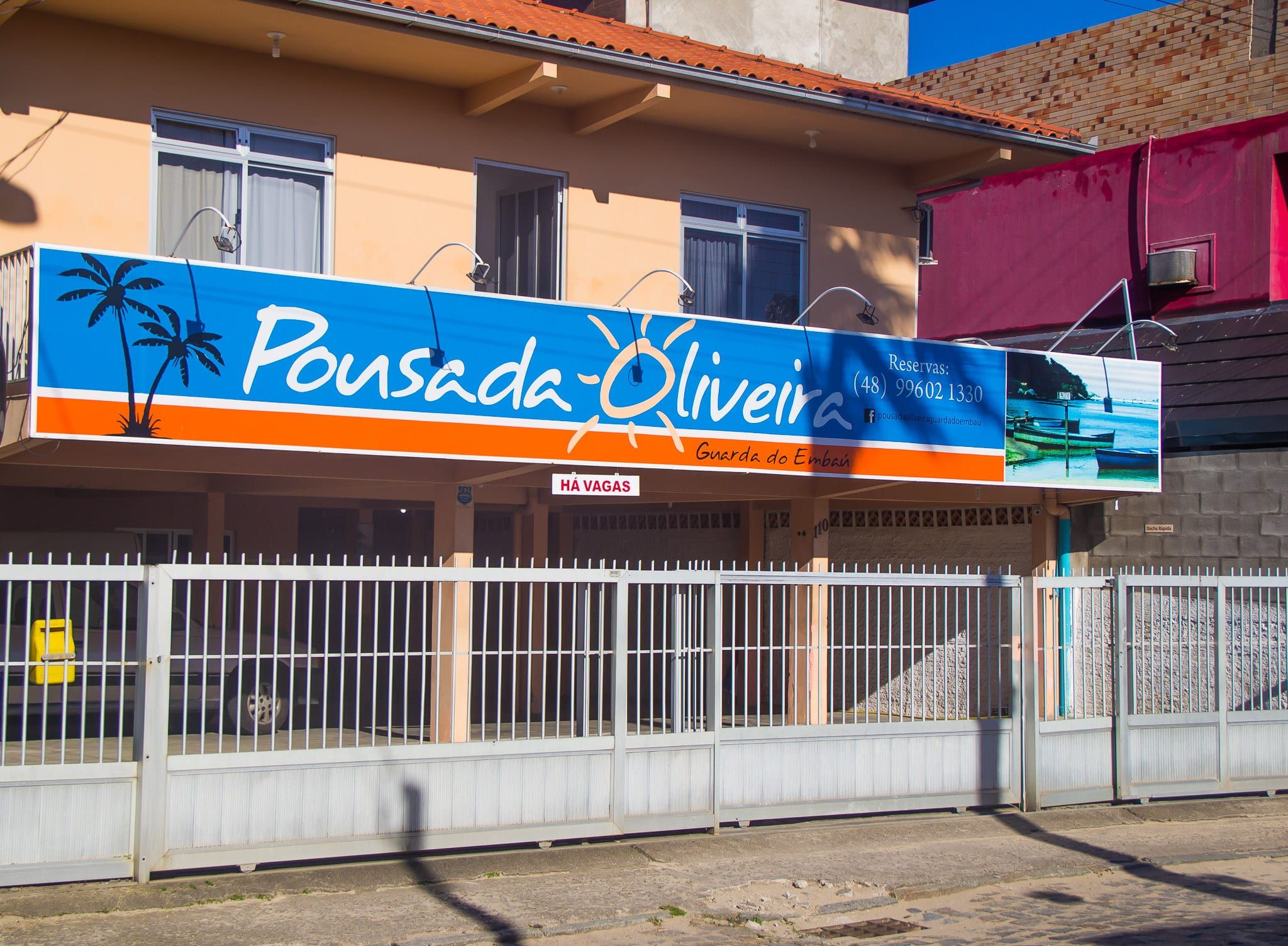 Fachada da Pousada Oliveira, com a placa azul e laranja